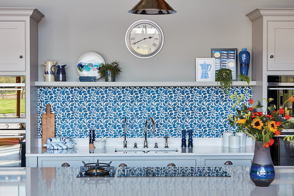 Tom Howley blue kitchen with colourful styled open shelving. 